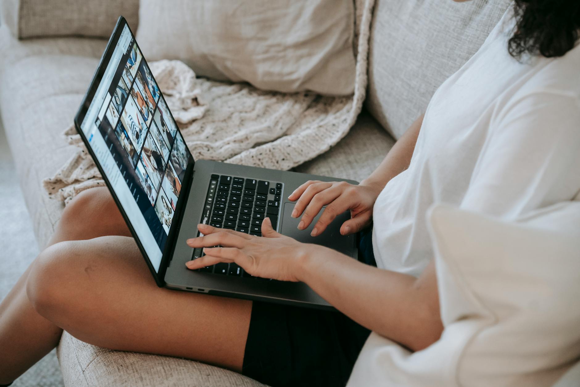 Kobieta na kanapie ogląda zdjęcia ofert na laptopie