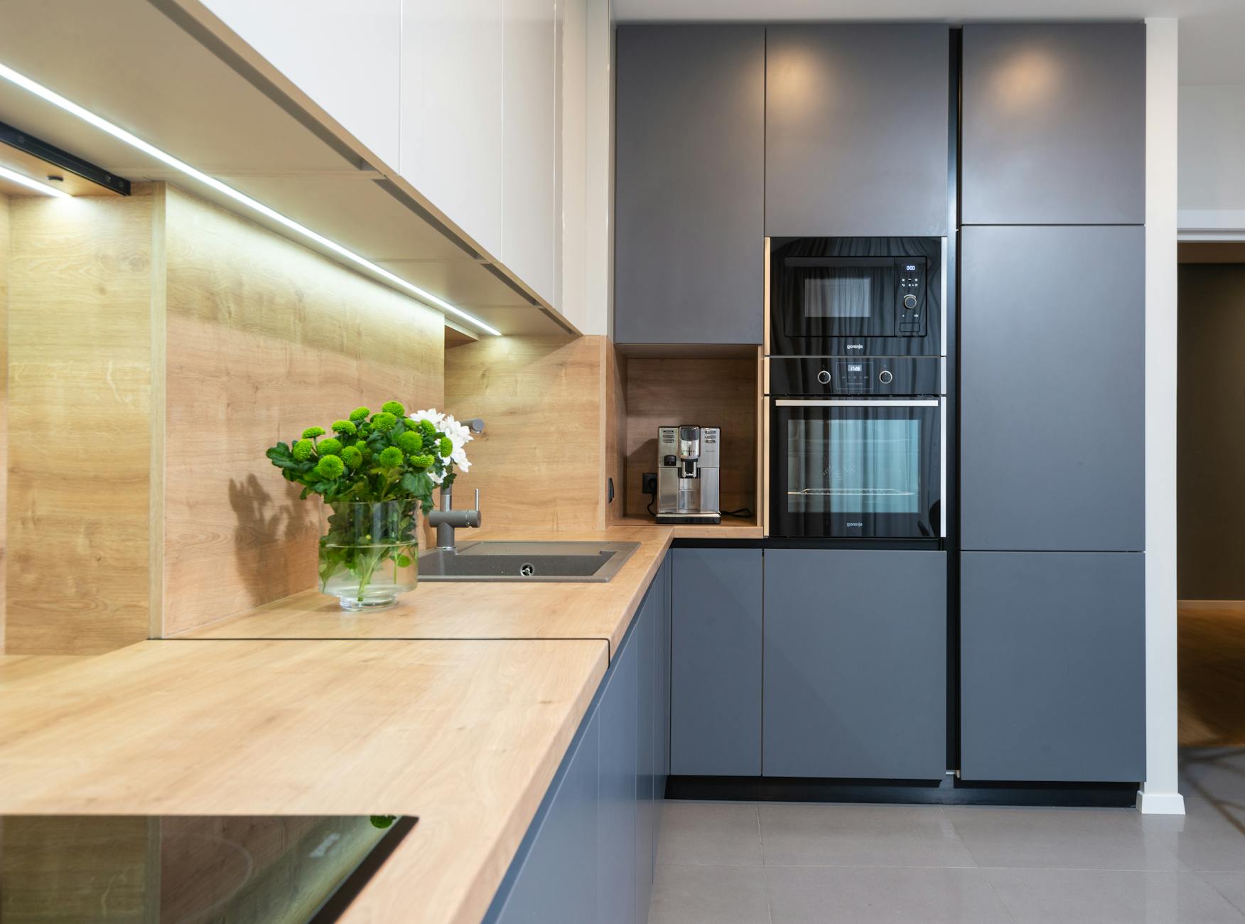 Nowoczesna kuchnia z piekarnikiem zabudowanym i wazonem z kwiatami