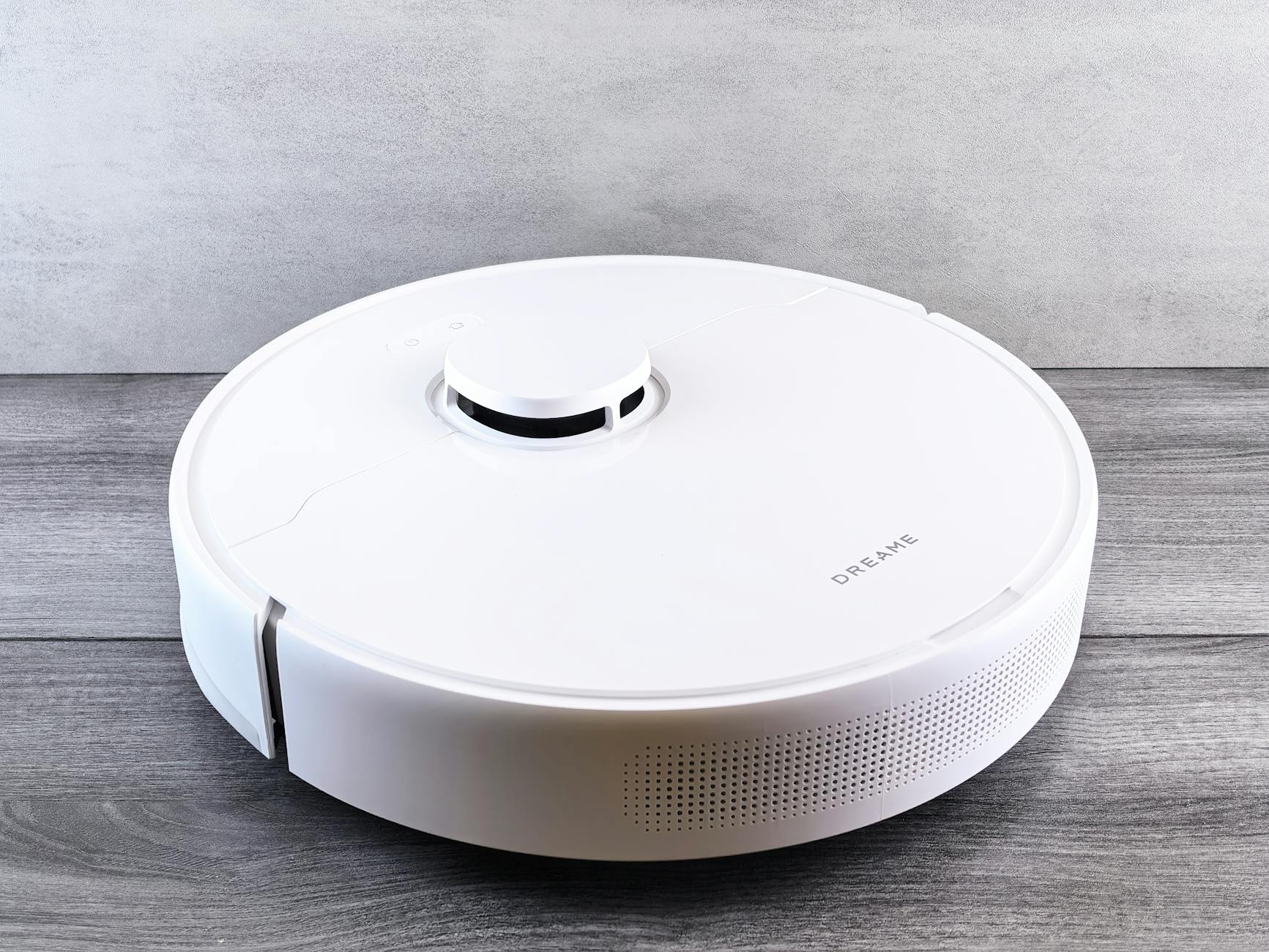 Biały robot sprzątający na drewnianej podłodze w nowoczesnym mieszkaniu