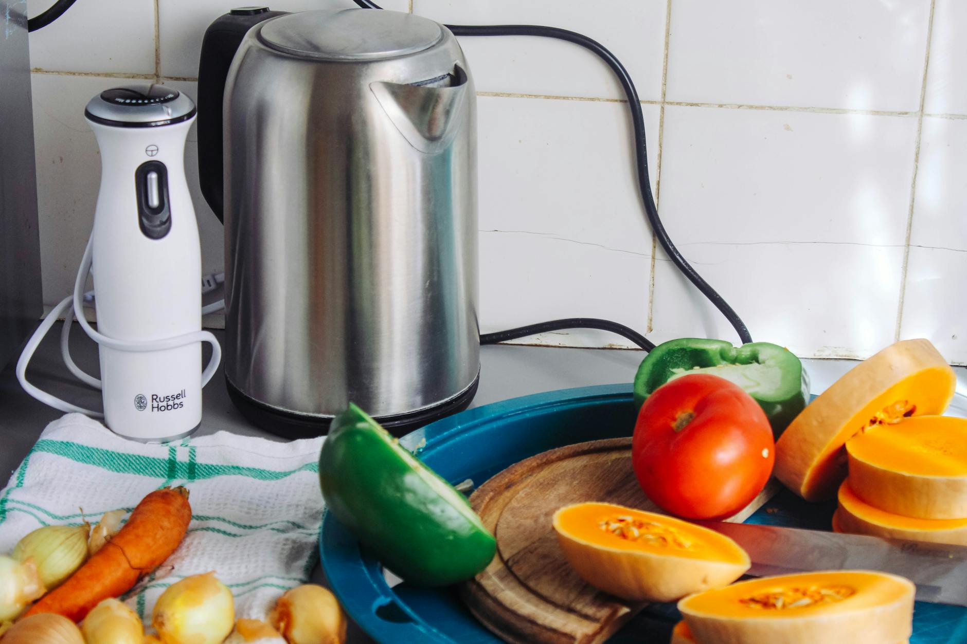 Czajnik elektryczny i blender na blacie wśród świeżych warzyw