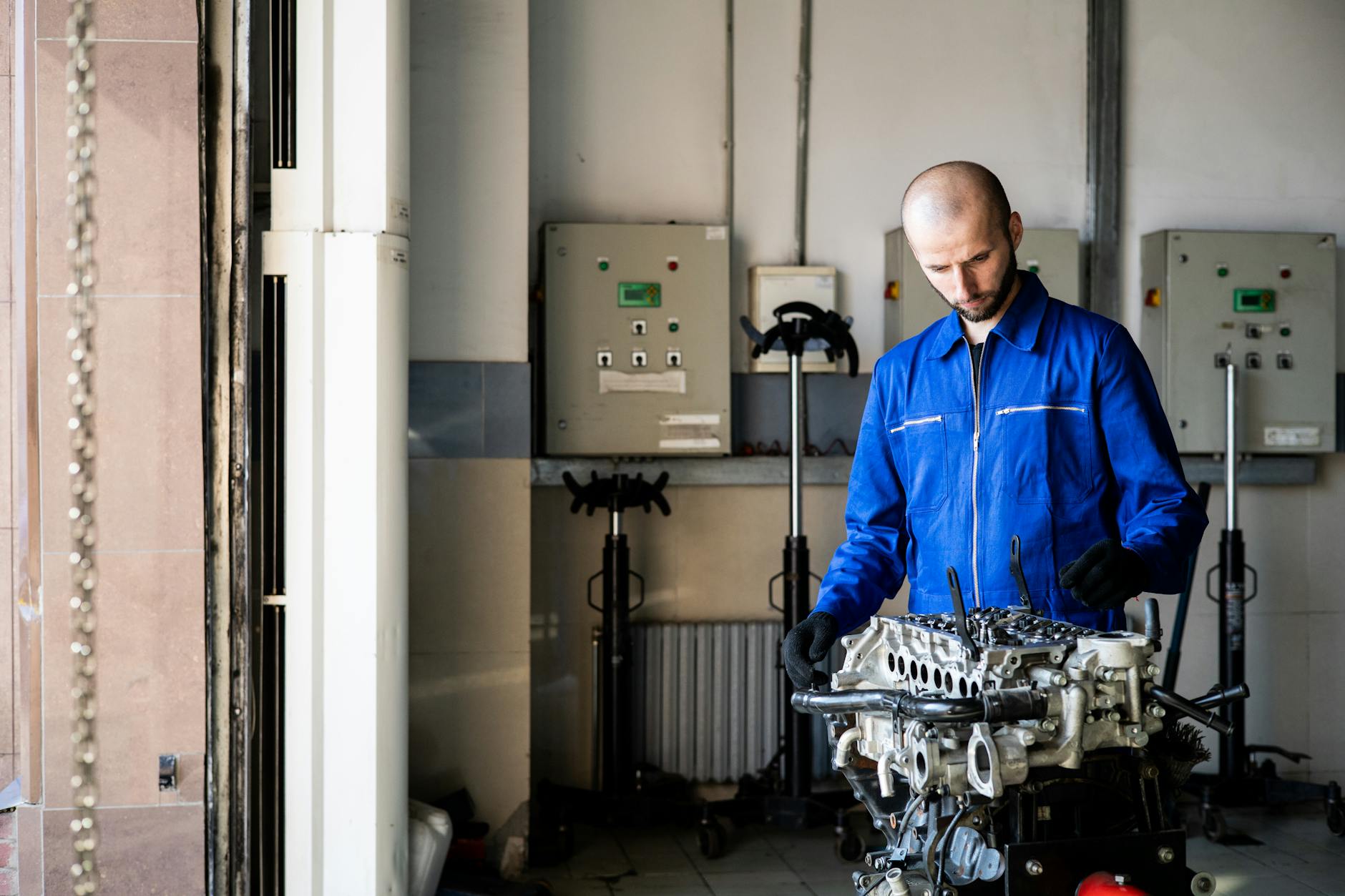 Mechanik w niebieskim kombinezonie naprawia urządzenie w warsztacie