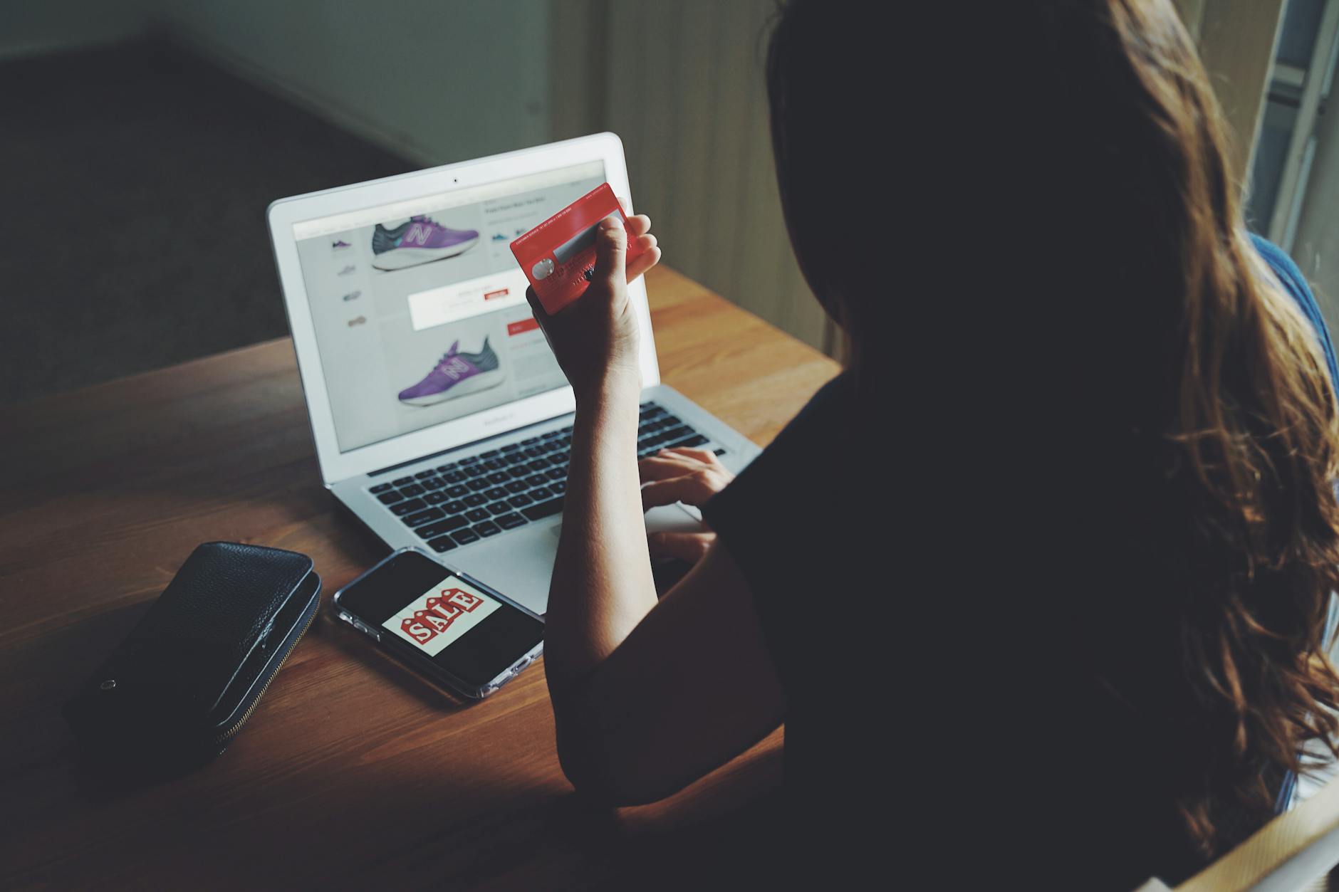 Kobieta przy drewnianym stole robi zakupy online laptopem i kartą