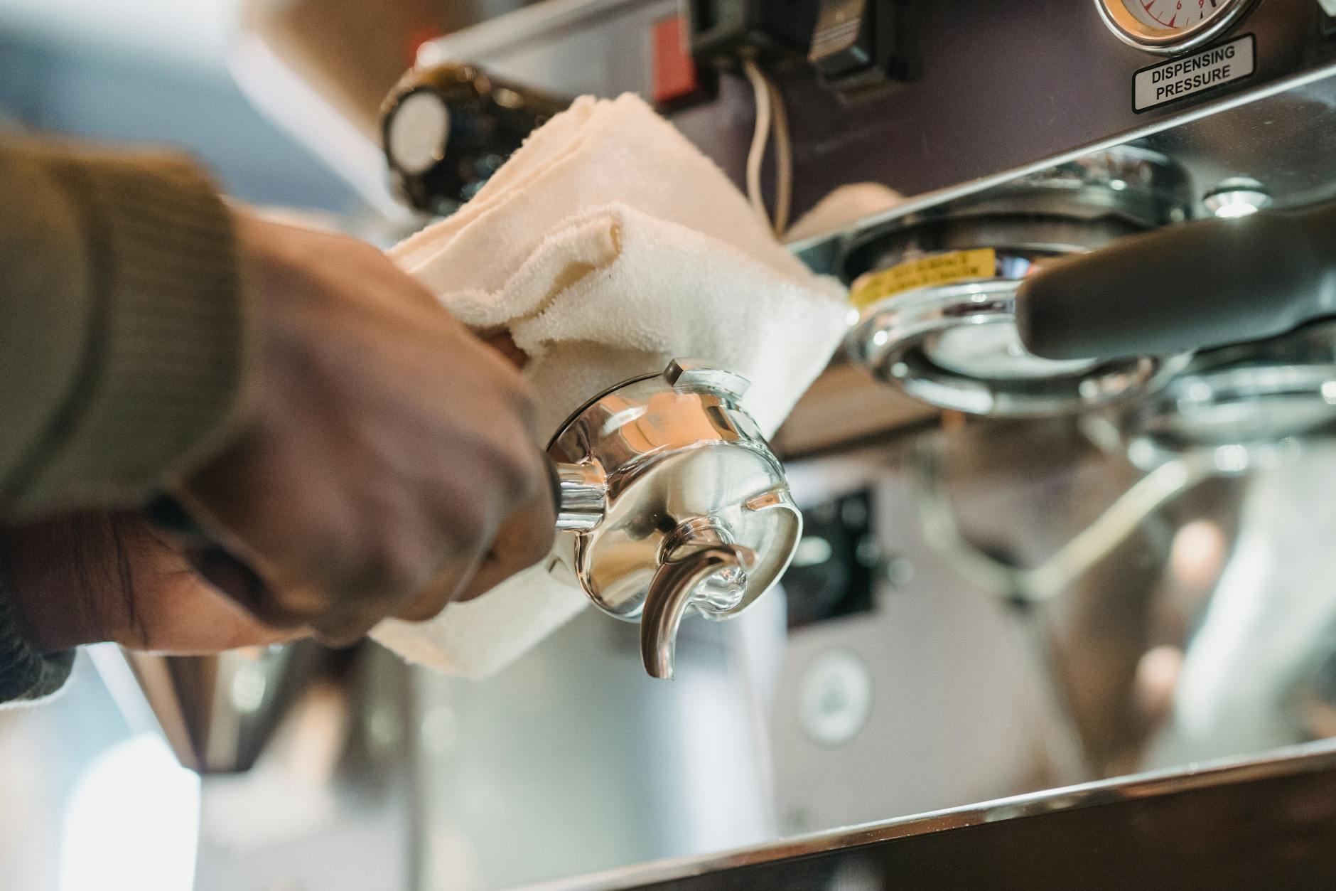Barista czyści kolbę ekspresu do kawy ściereczką
