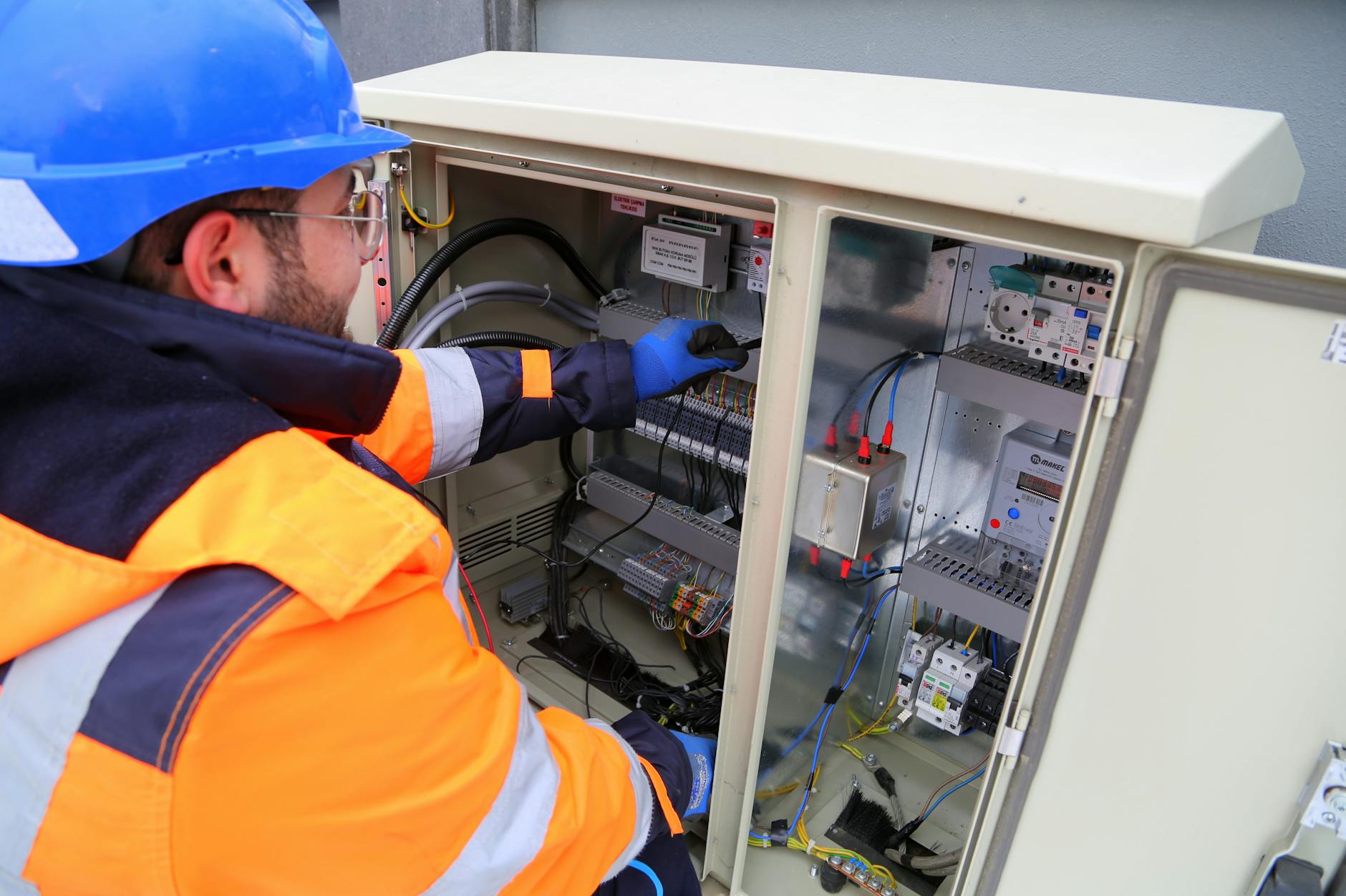 Inżynier w kasku sprawdza zewnętrzną szafę elektryczną