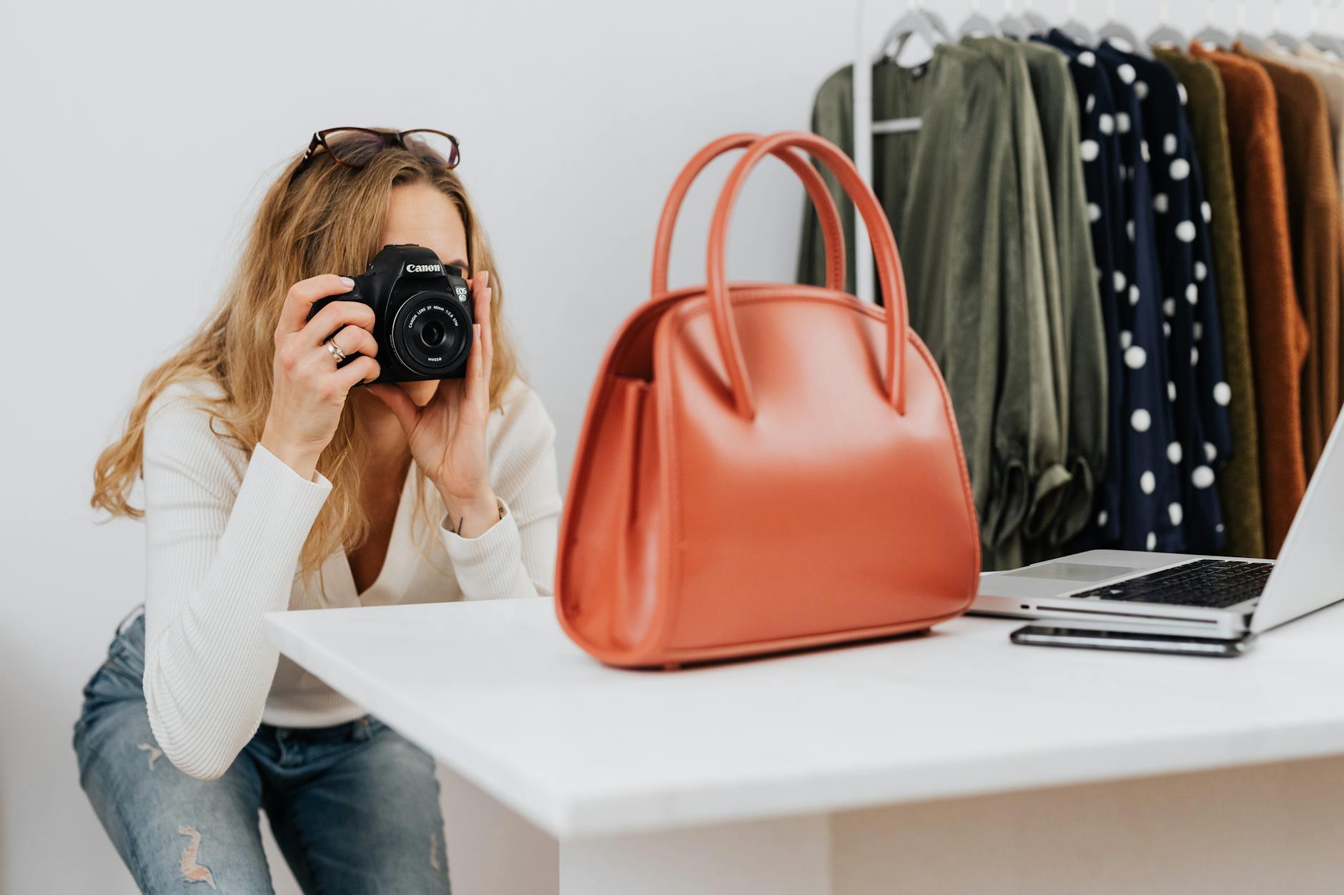 Kobieta fotografuje torebkę aparatem w domowym studio