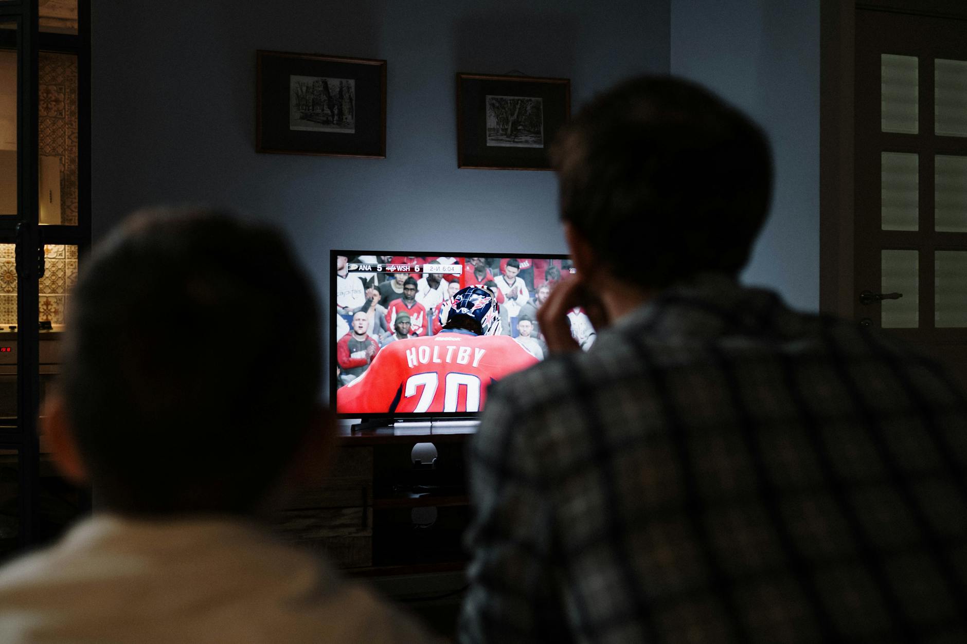 Telewizor powystawowy: jak sprawdzić matrycę, wypalenia i martwe piksele przed zapłatą w outlecie Ojciec i syn oglądają mecz hokeja na telewizorze w salonie