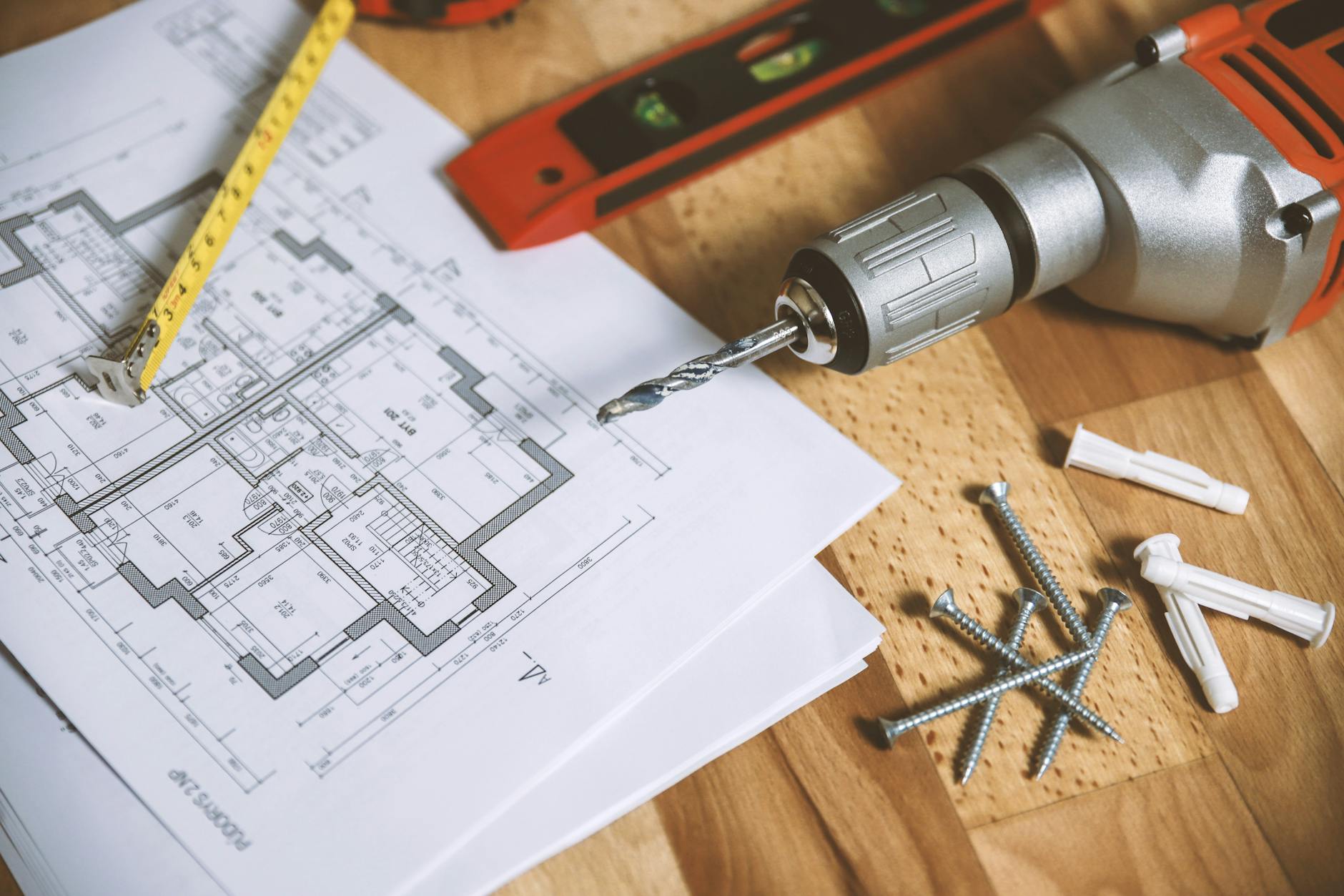 Plan mieszkania na biurku z wiertarką i śrubami