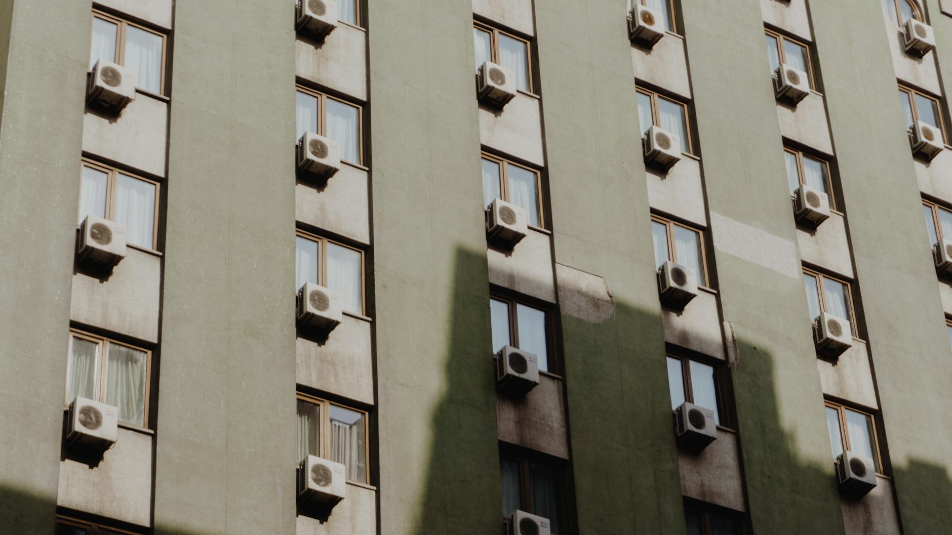 Elewacja kamienicy z licznymi klimatyzatorami w oknach