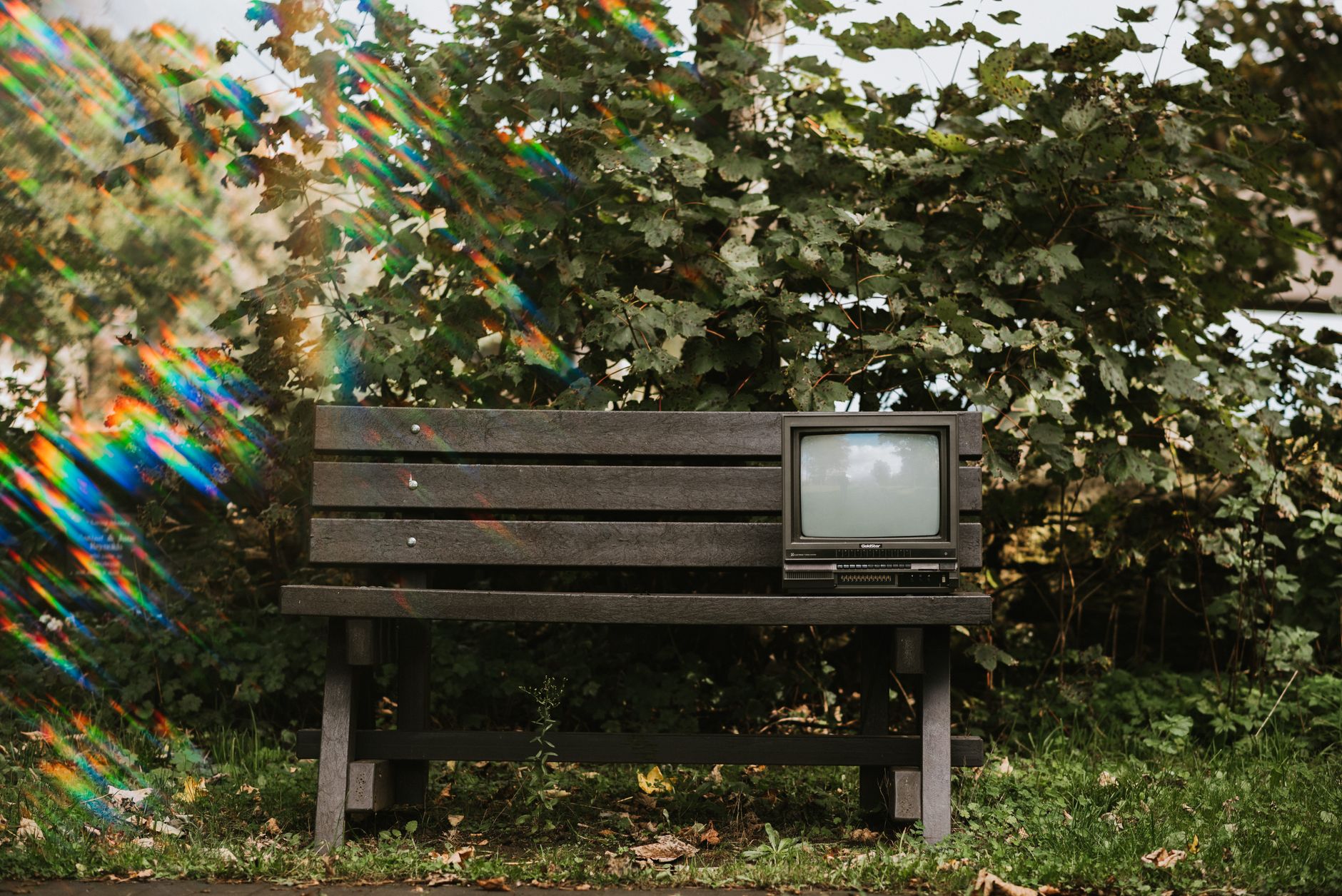 Mały czarny stary telewizor na ławce na trawie w słoneczny dzień