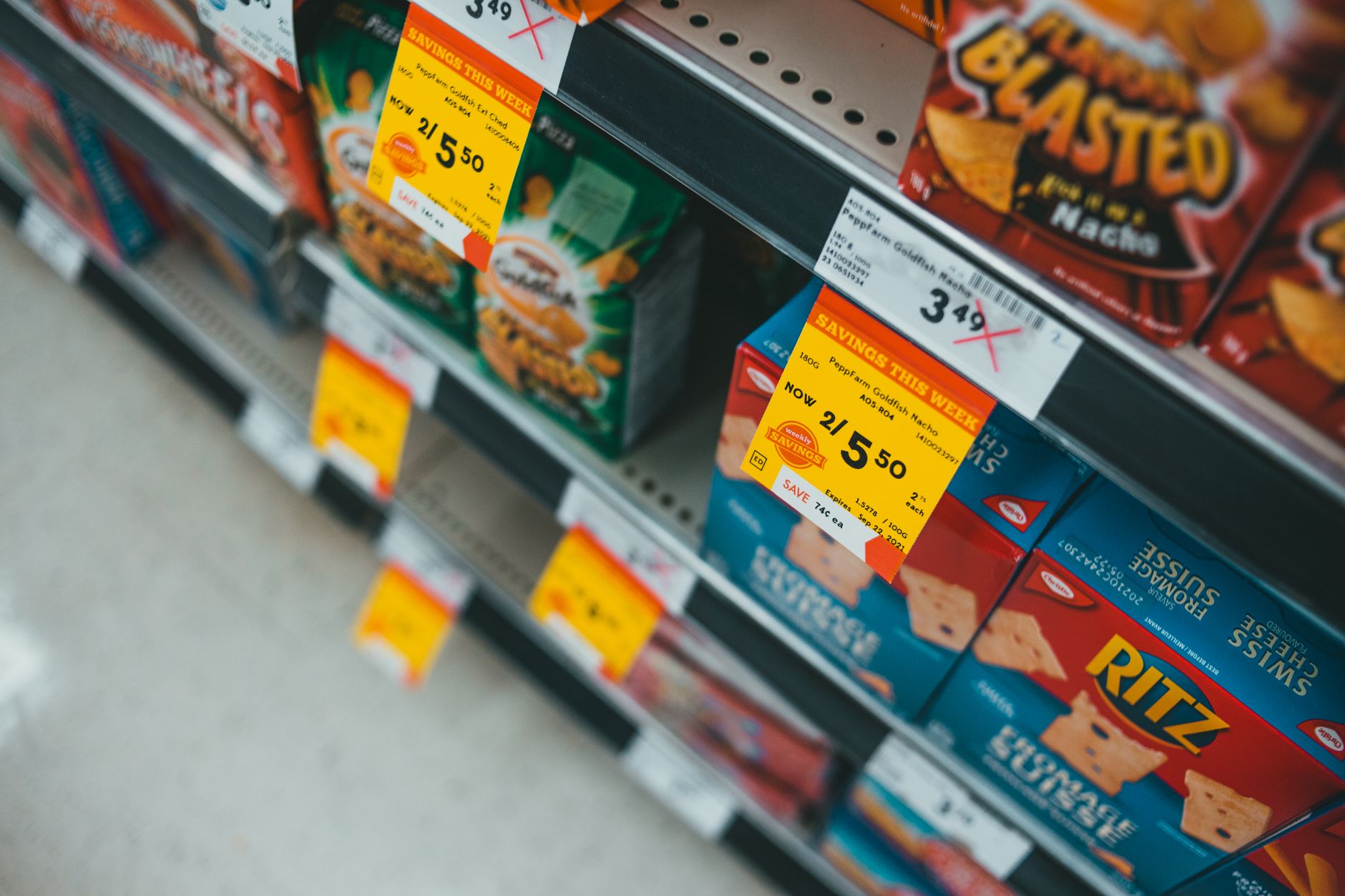Alejka supermarketu z przecenionymi przekąskami i wyraźnymi etykietami cen