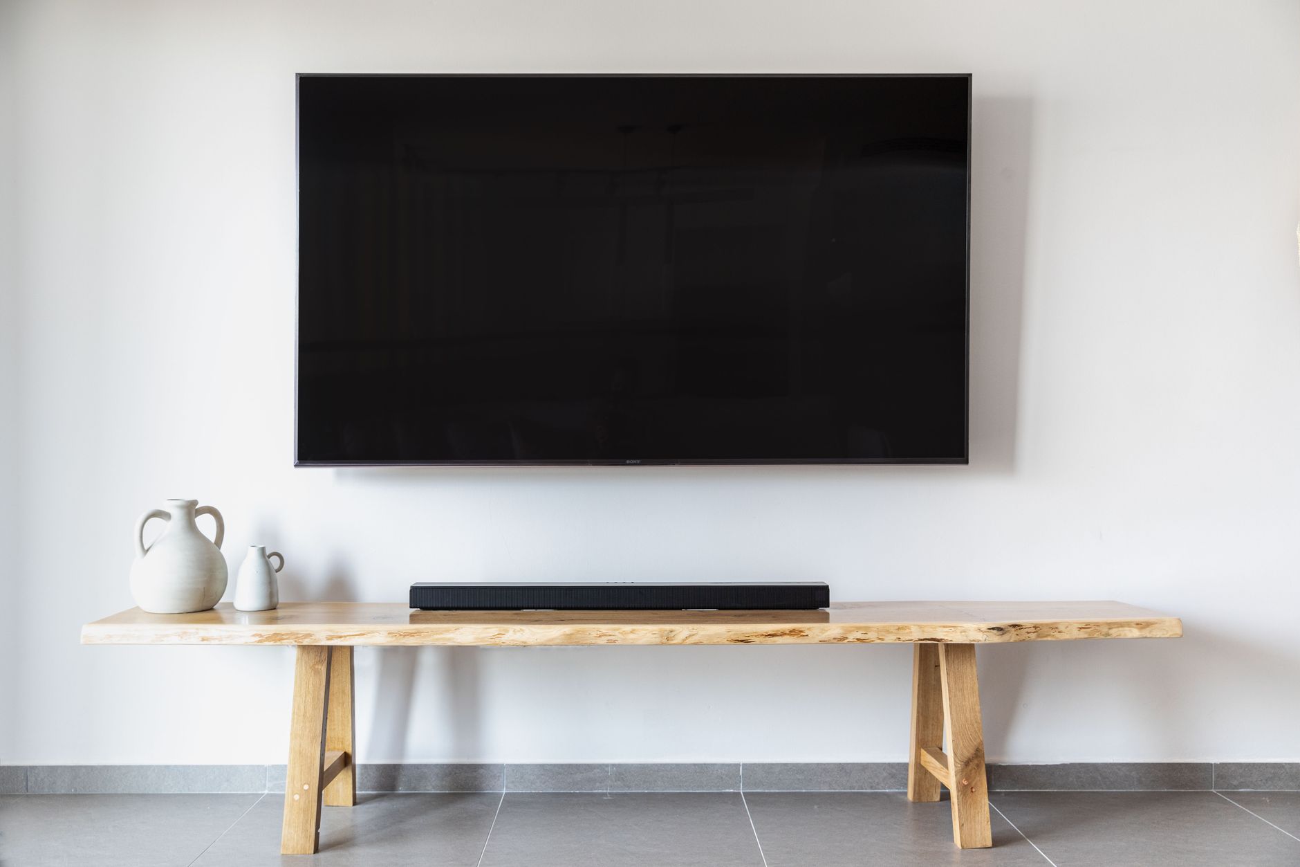 Minimalistyczny salon z telewizorem na ścianie i drewnianą szafką RTV Minimalistyczny salon z telewizorem na ścianie i drewnianą szafką RTV