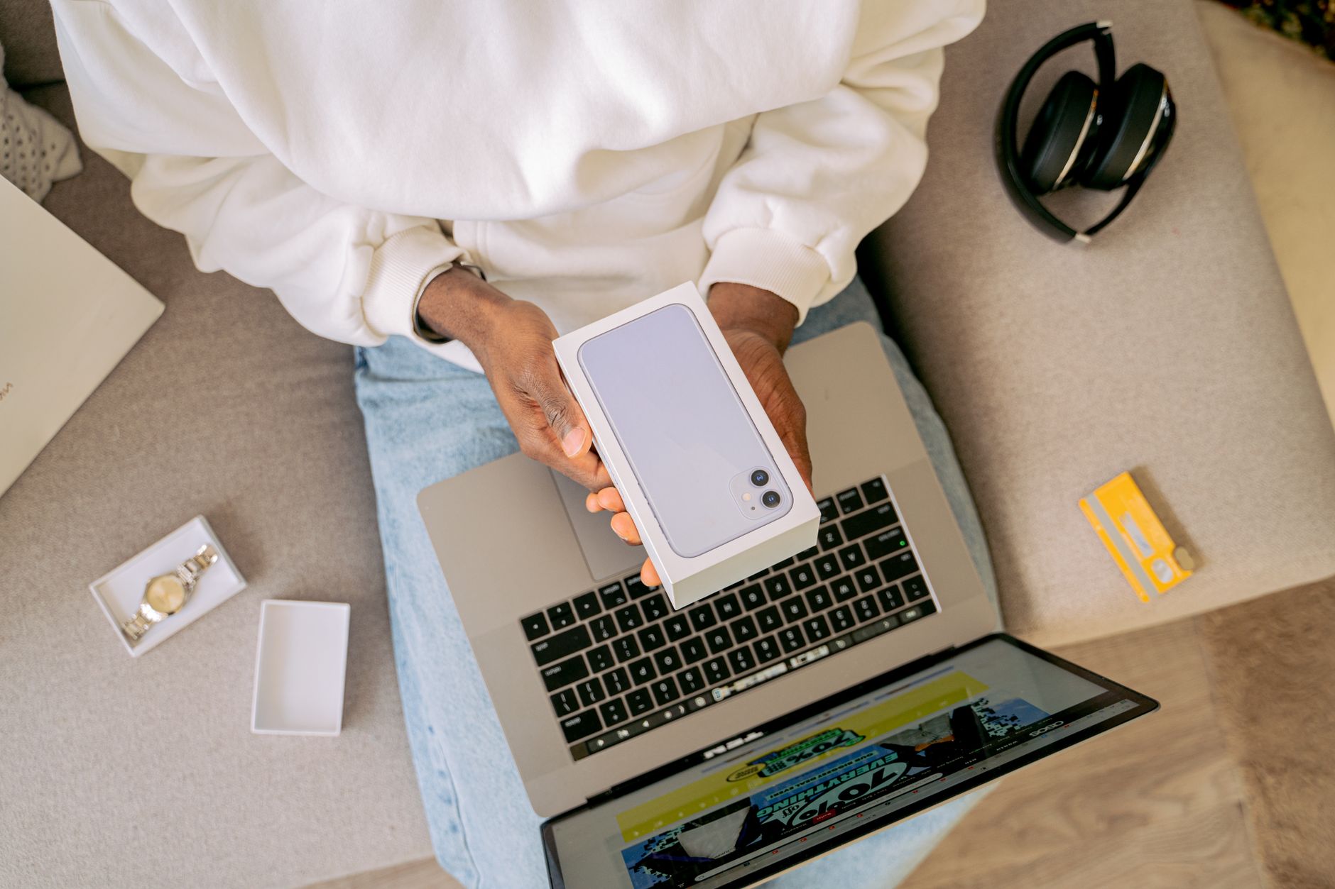 Osoba rozpakowuje nowy smartfon podczas zakupów online na kanapie