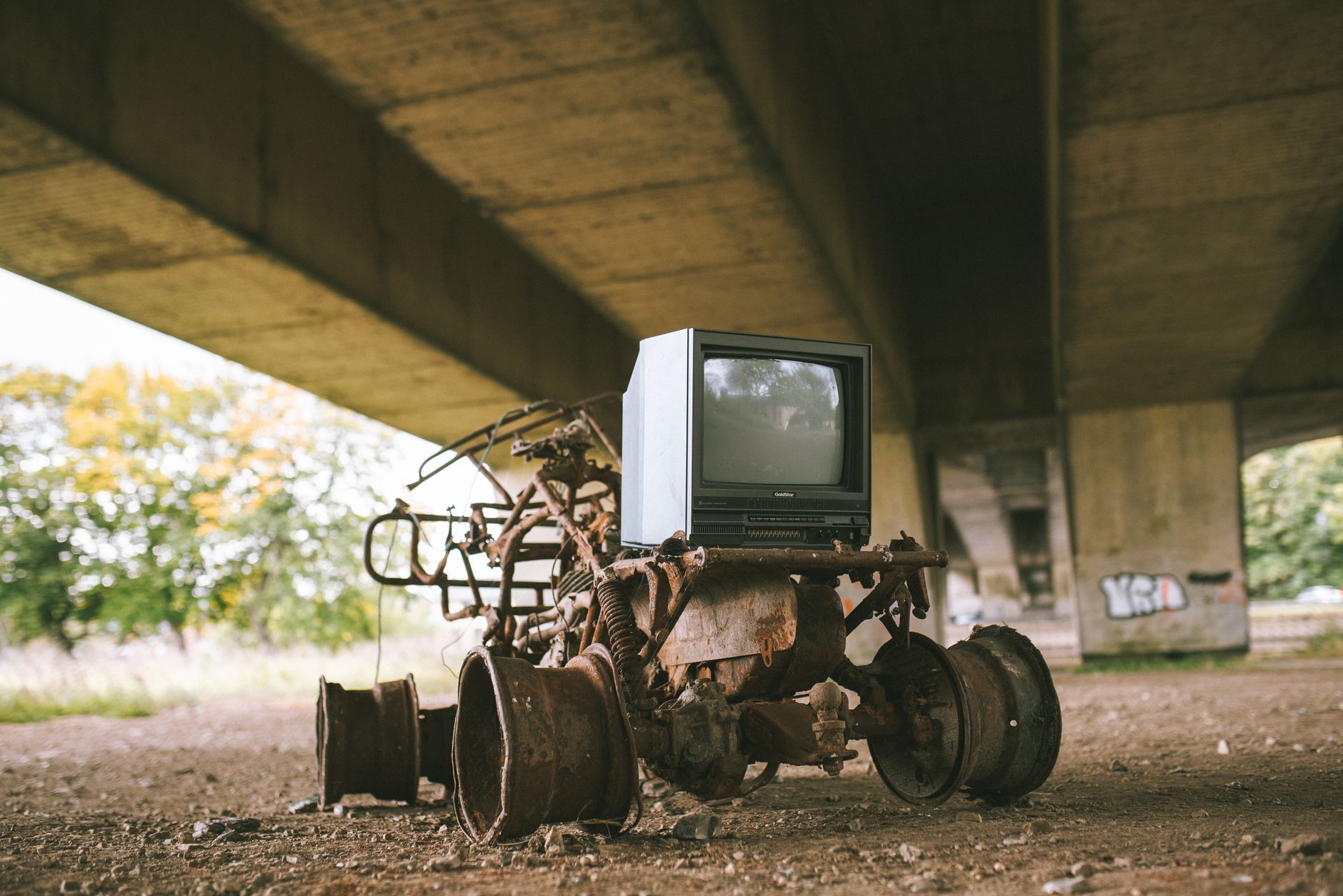Stary uszkodzony samochód z retro telewizorem pod mostem