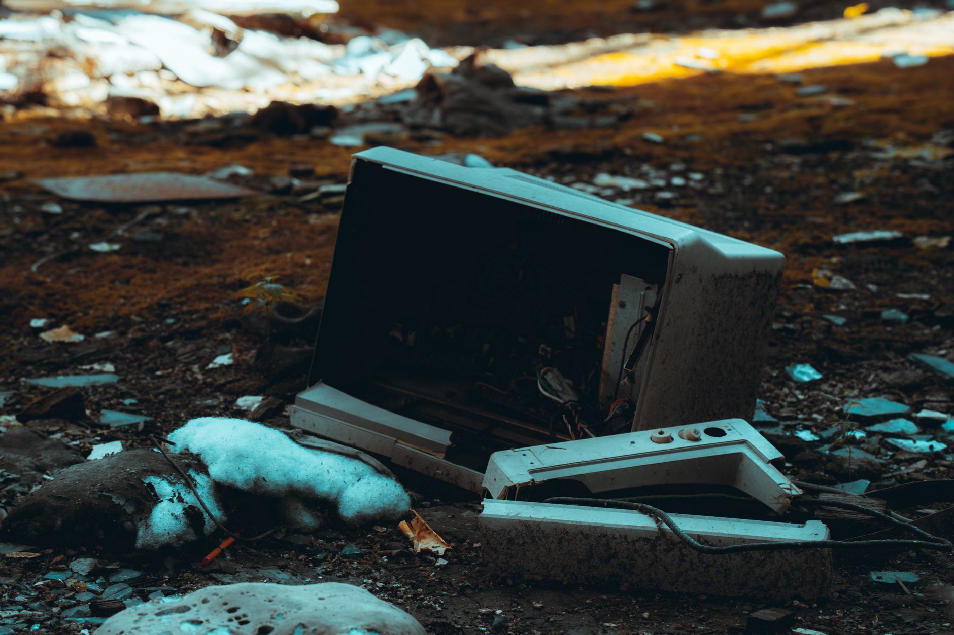Zniszczony telewizor z pękniętym ekranem leżący wśród miejskich gruzów